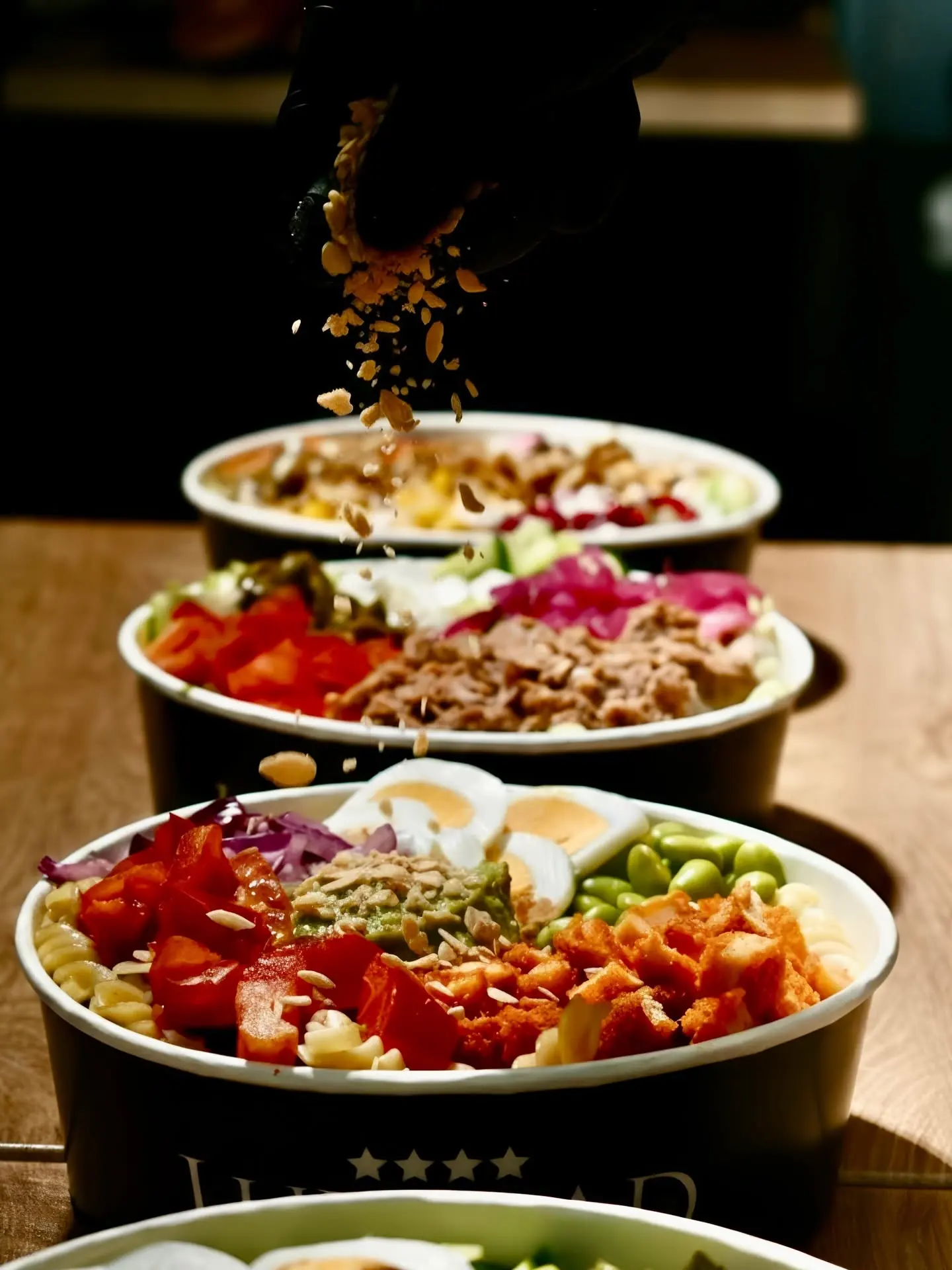 A row of Luxalad bowls with ingredients falling into them