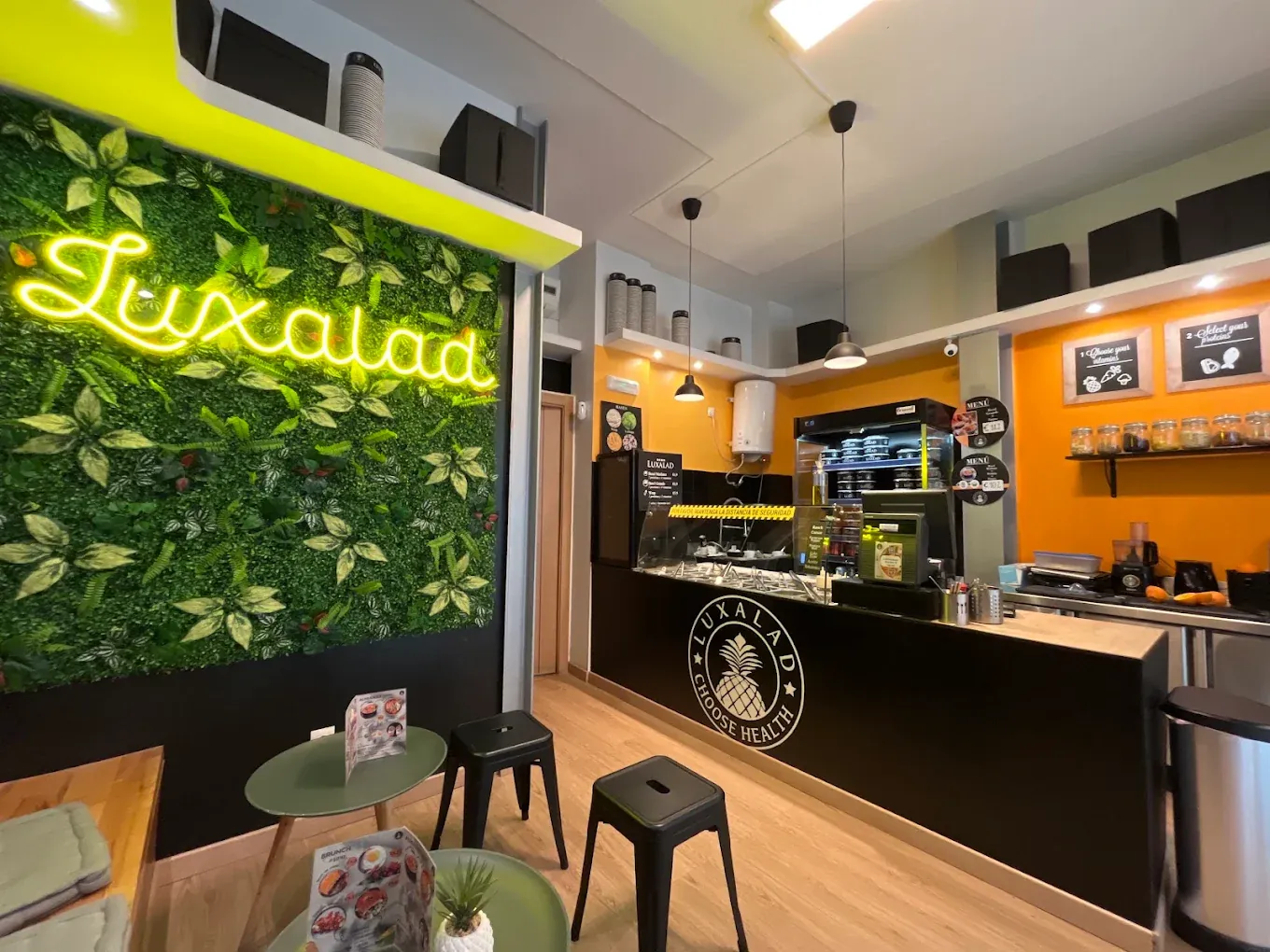 The green neon Luxalad sign inside the Málaga salad bar